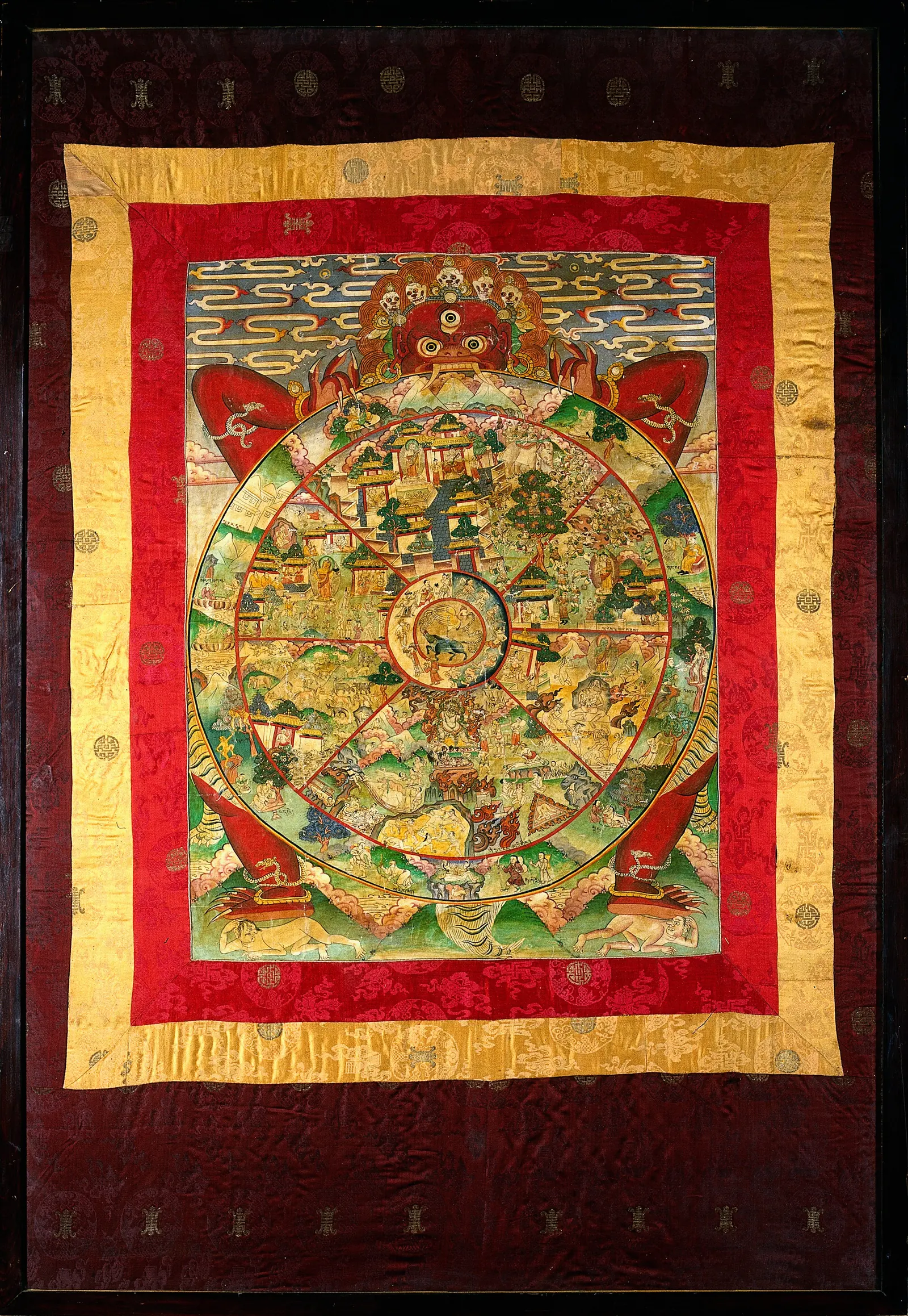 A Tibetan painting of Yama holding the Wheel of Life, the cycle of rebirth driven by karma, in rich reds, greens and golds.