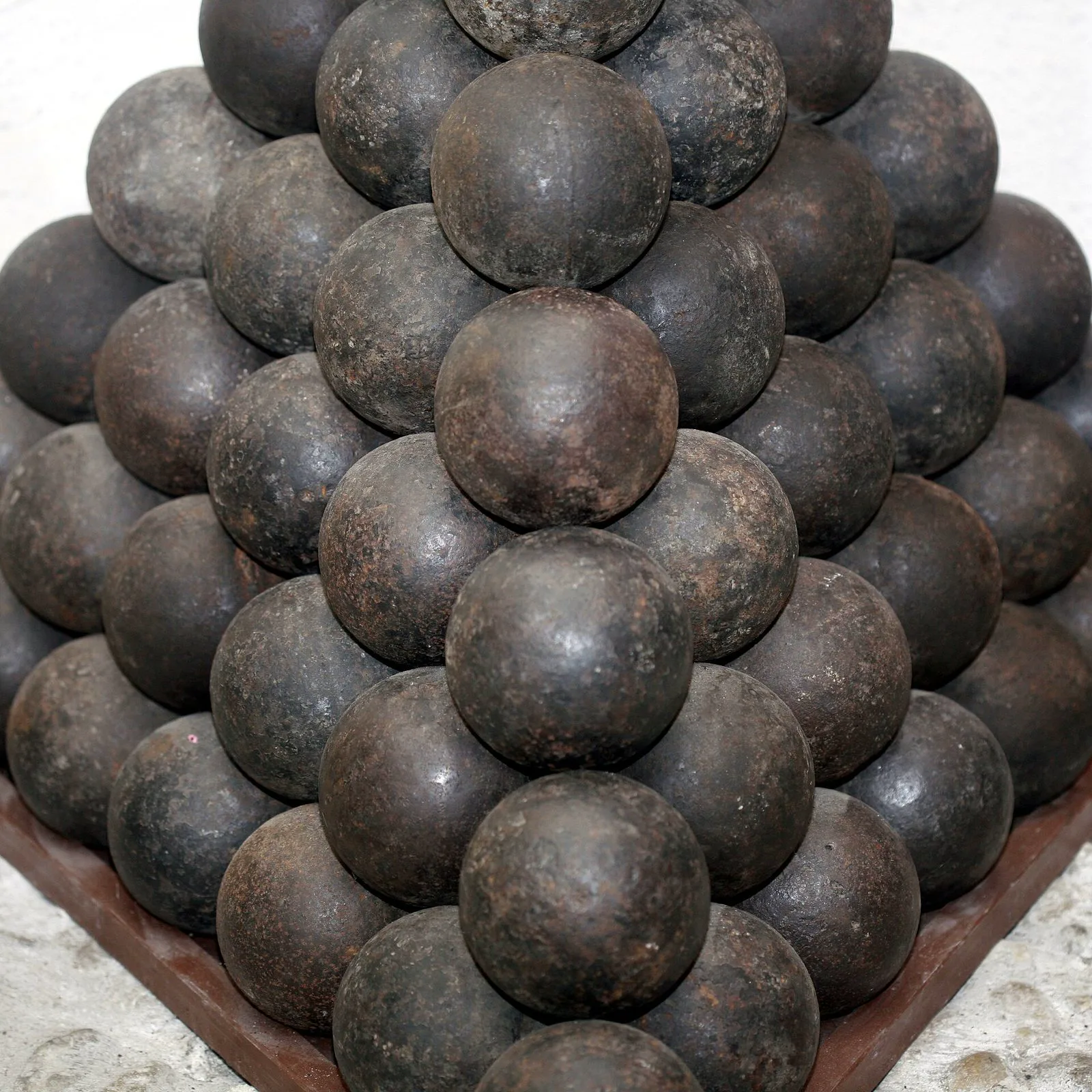 Iron cannonballs stacked in a tight pyramid, the everyday picture of sphere packing.