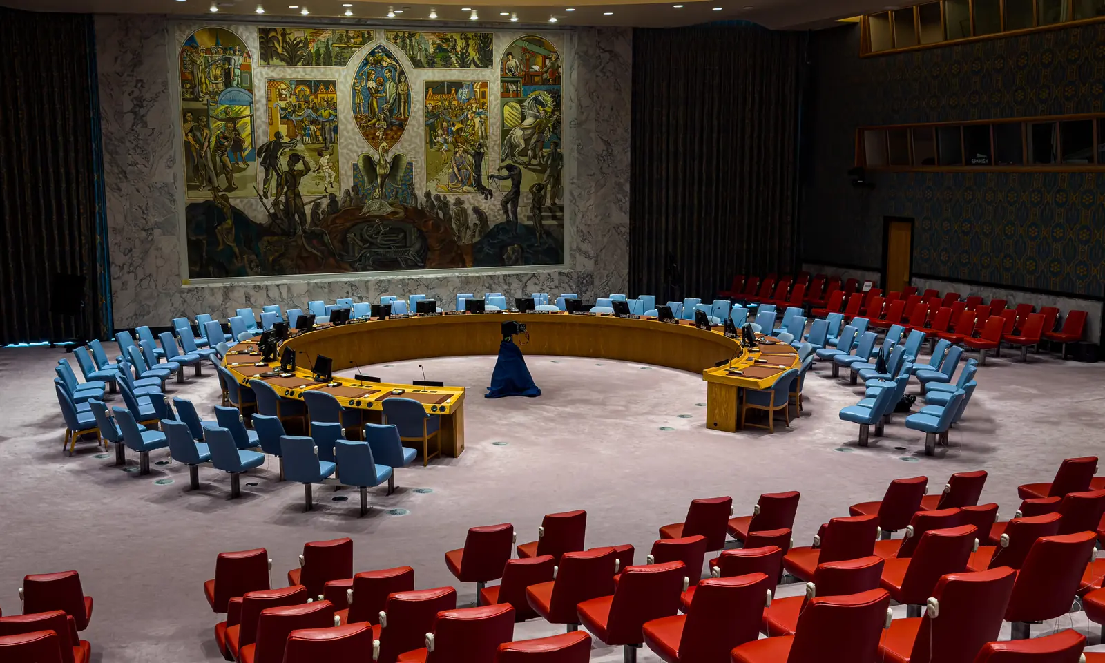 The UN Security Council chamber in New York, the horseshoe table beneath Per Krohg's large mural.