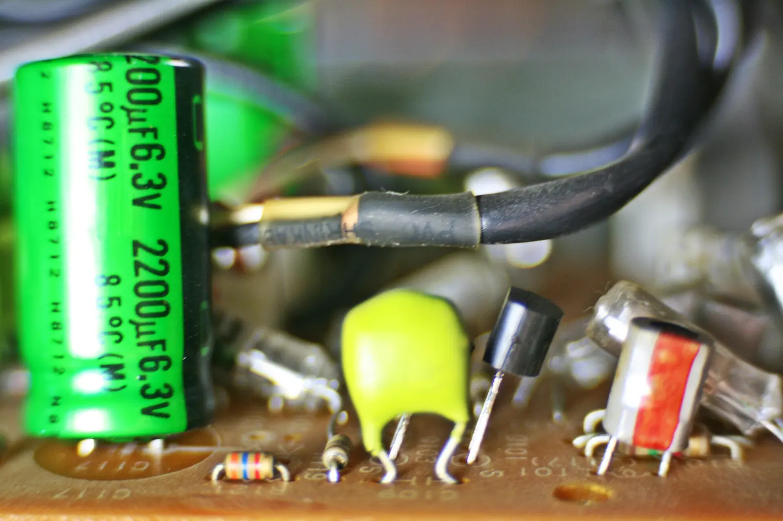A macro photograph of a circuit board, green mask and metal traces.