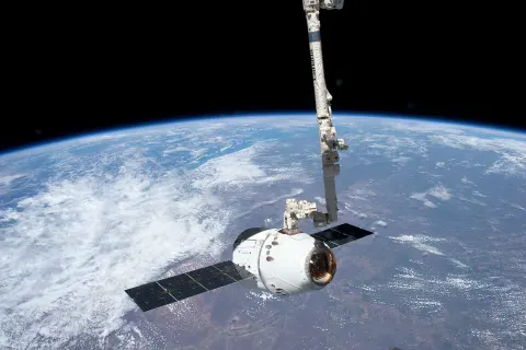 A SpaceX Dragon spacecraft held by Canadarm2 at the International Space Station.