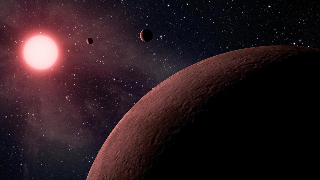 Artist’s picture of a small red star with three rocky planets packed close, like a miniature Jupiter family.